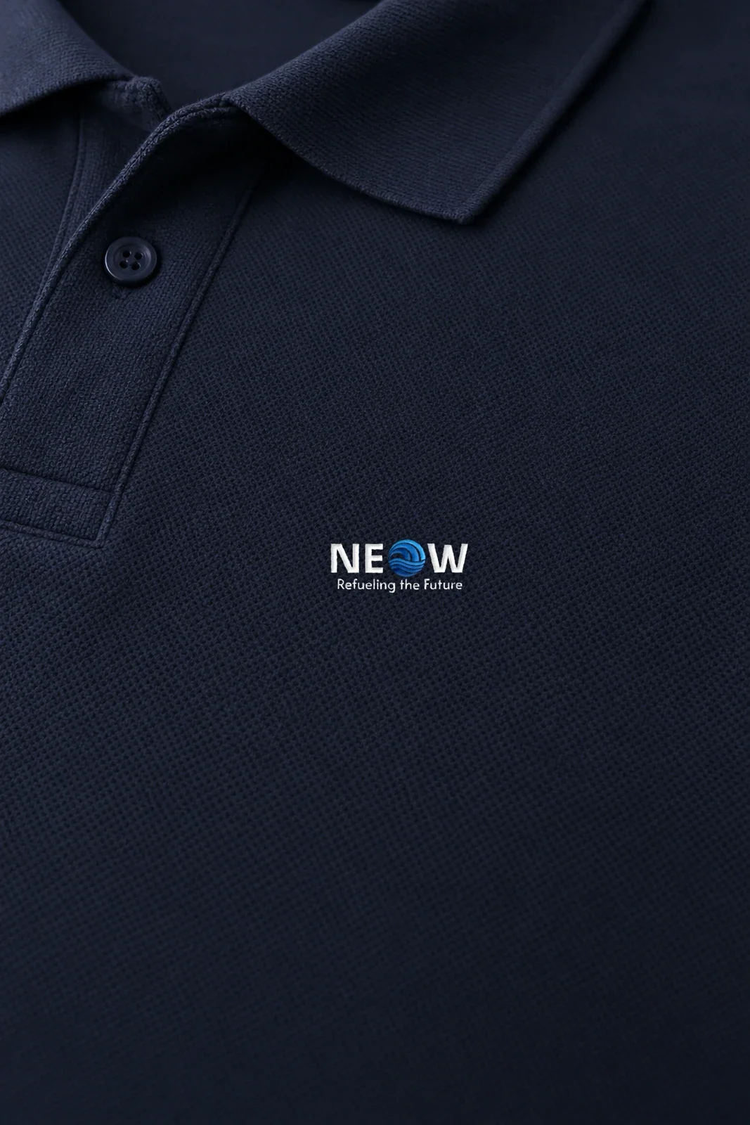 Close-up of the embroidered NEOW lockup on the navy pique, next to the placket
